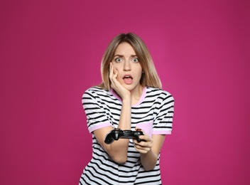 Photo of Emotional young woman playing video games with controller on color background