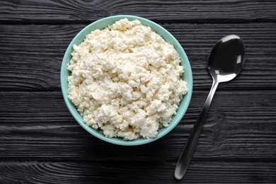 Delicious fresh cottage cheese on black wooden table, flat lay