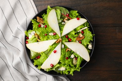 Delicious pear salad in bowl on wooden table, top view