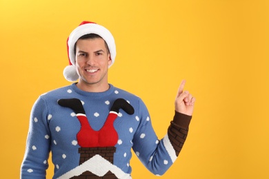 Photo of Handsome man wearing Santa hat on yellow background, space for text