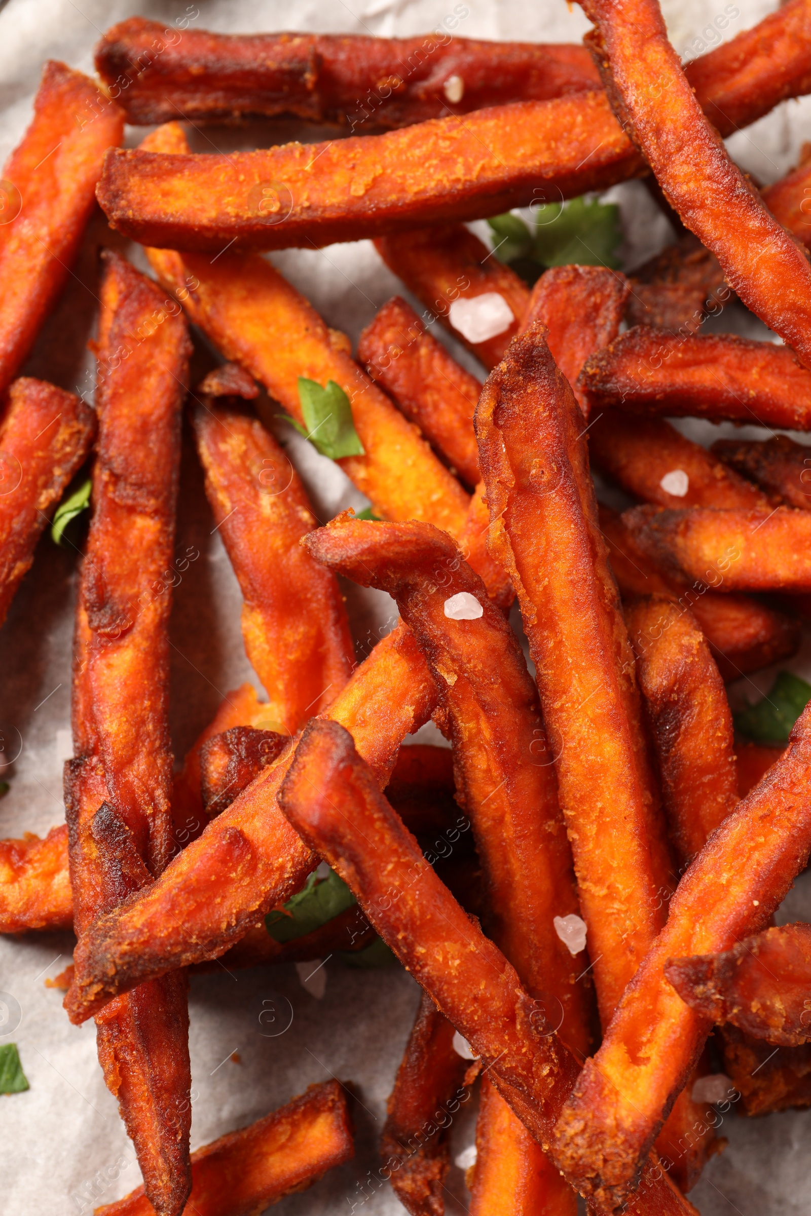 Photo of Delicious sweet potato fries on parchment paper, closeup