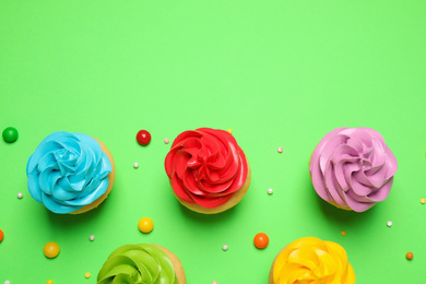 Photo of Colorful birthday cupcakes on green background, flat lay. Space for text