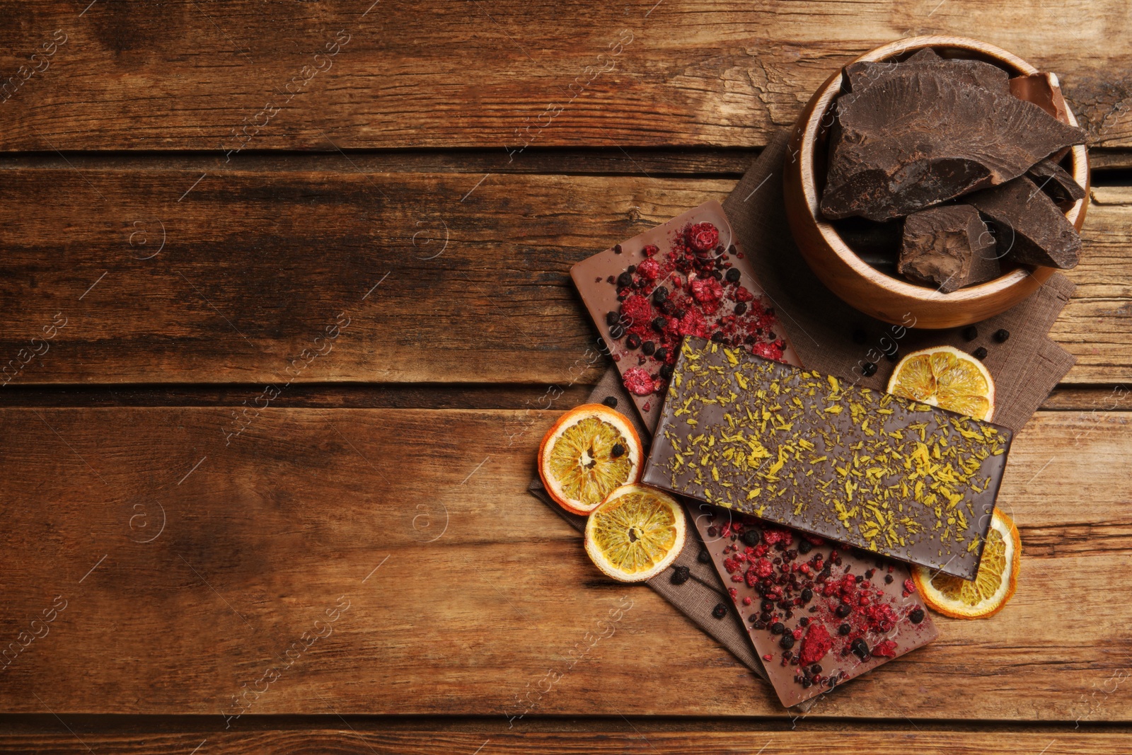 Photo of Different chocolate bars with freeze dried fruits on wooden table, flat lay. Space for text