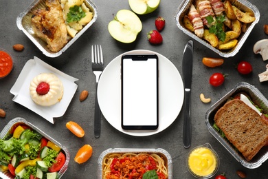 Photo of Flat lay composition with lunchboxes and smartphone on grey table, mockup for design. Healthy food delivery