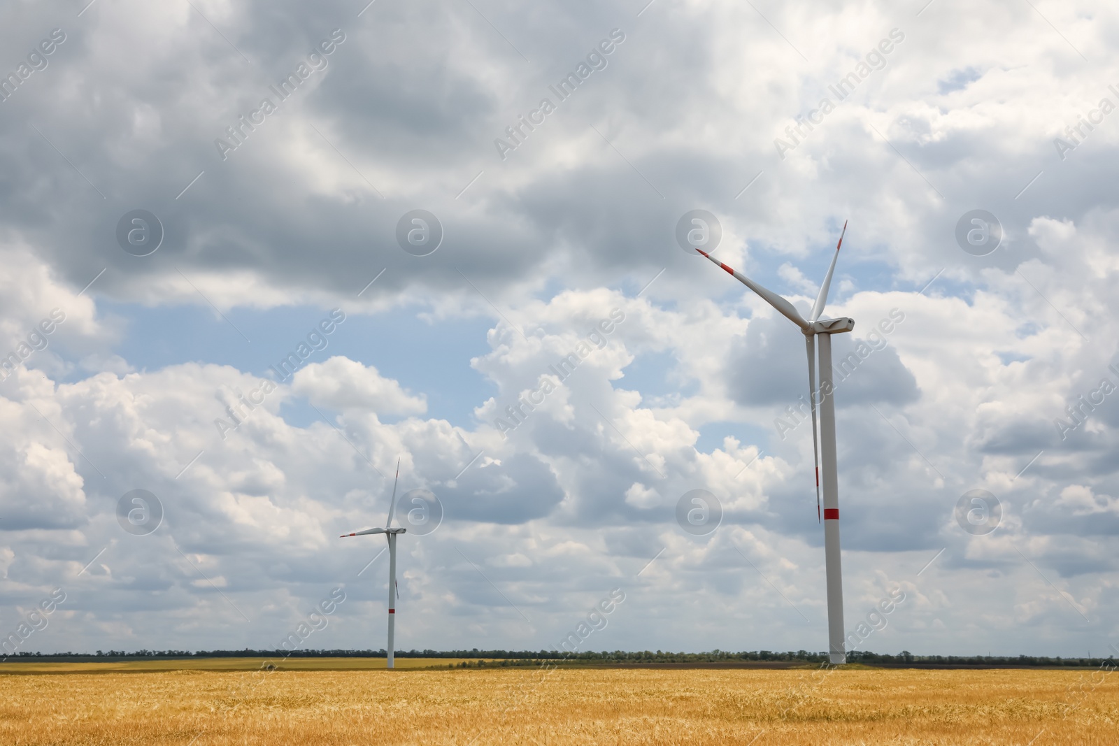 Photo of Modern wind turbines in field on cloudy day. Alternative energy source