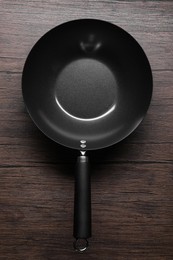 Photo of Empty iron wok on wooden table, top view. Chinese cookware