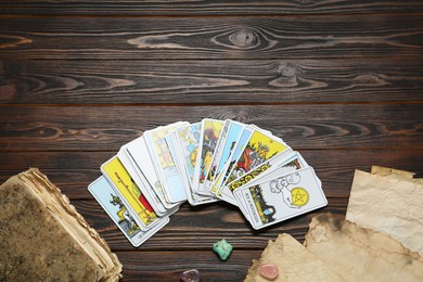 Photo of Tarot cards, old book and crystals on wooden table, flat lay