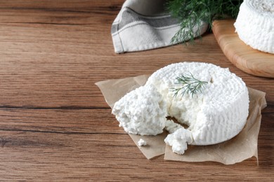 Photo of Delicious cottage cheese with dill on wooden table, space for text