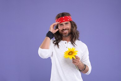 Photo of Stylish hippie man with sunflower on violet background