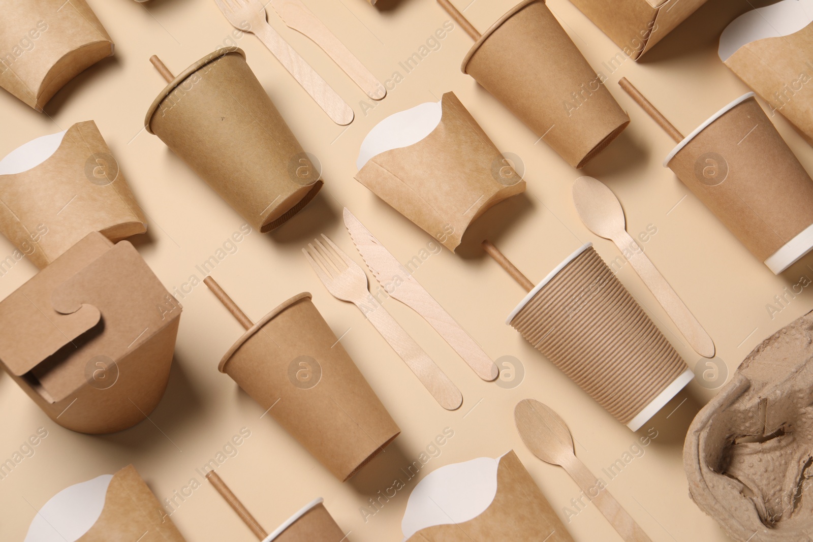 Photo of Eco friendly food packaging. Paper containers and wooden cutlery on beige background, above view