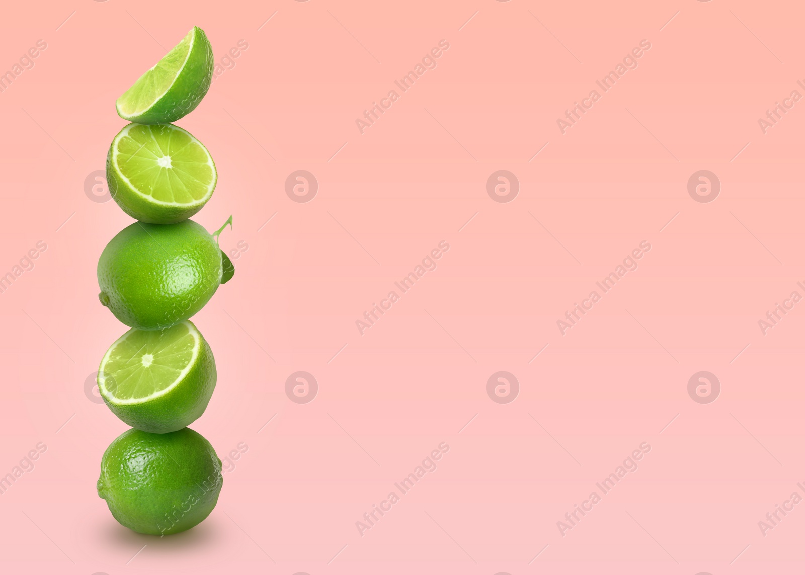 Image of Stacked whole and cut limes on light pink background, space for text