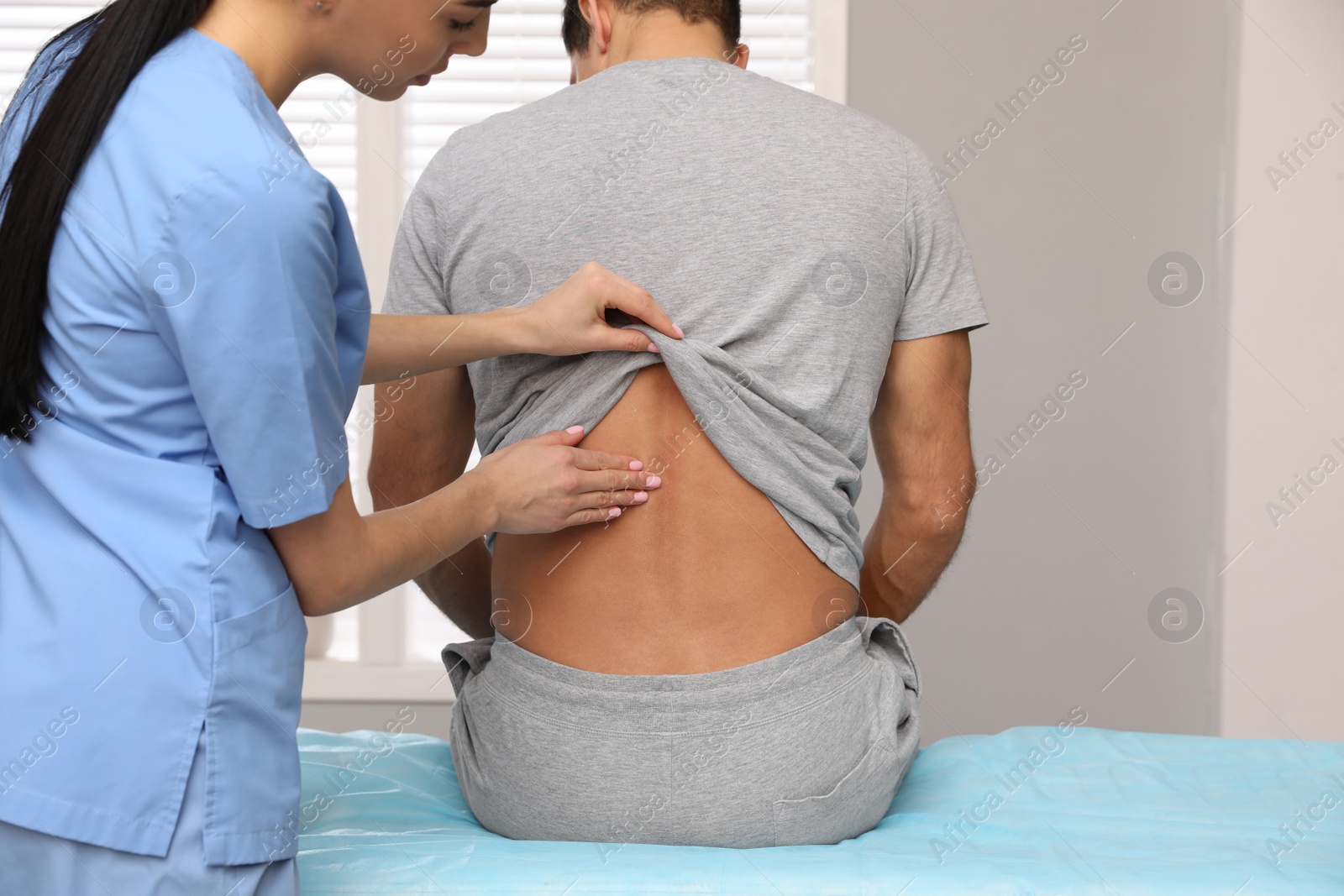 Photo of Orthopedist examining man's back in clinic. Scoliosis treatment