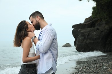 Photo of Young couple kissing on beach near sea. Space for text