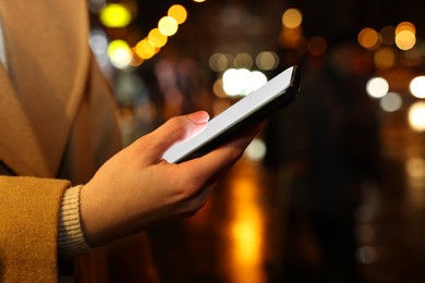 Photo of Woman with smartphone on night city street, closeup. Space for text