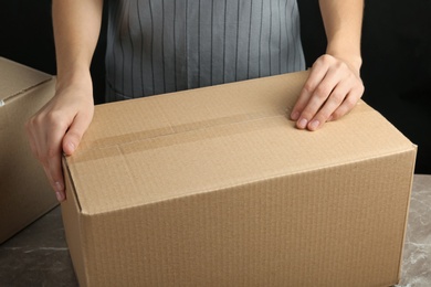 Photo of Woman packing box at table, closeup. Space for design