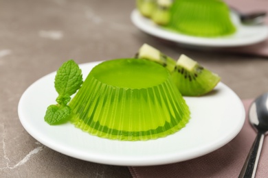 Plate with kiwi jelly and mint served on beige table, closeup