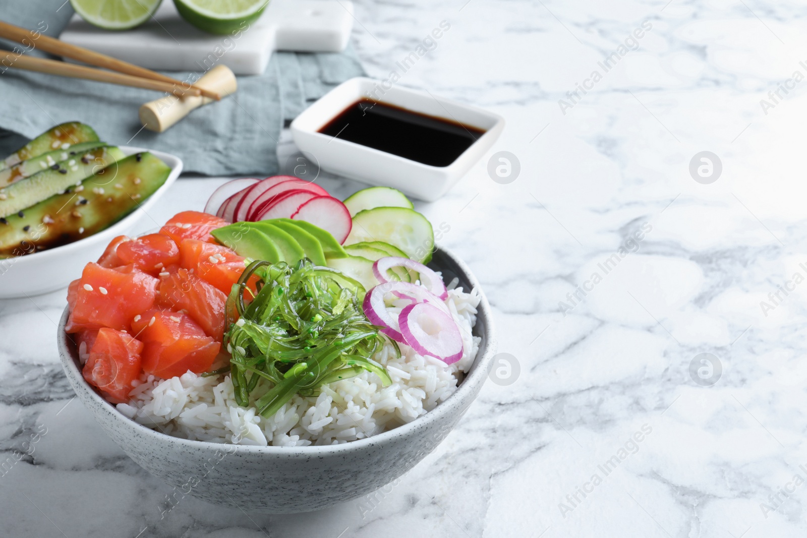 Photo of Delicious poke bowl with salmon and vegetables served on white marble table. Space for text