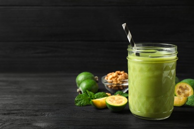 Photo of Fresh feijoa smoothie and fresh ingredients on black wooden table. Space for text