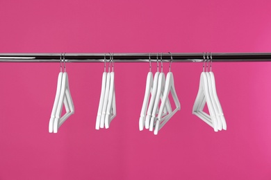 Metal rack with clothes hangers on color background