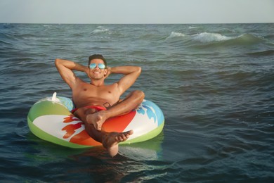 Man with inflatable ring resting in sea