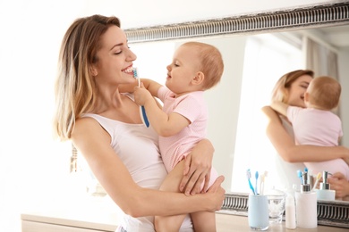 Photo of Woman holding daughter with toothbrush in bathroom. Space for text