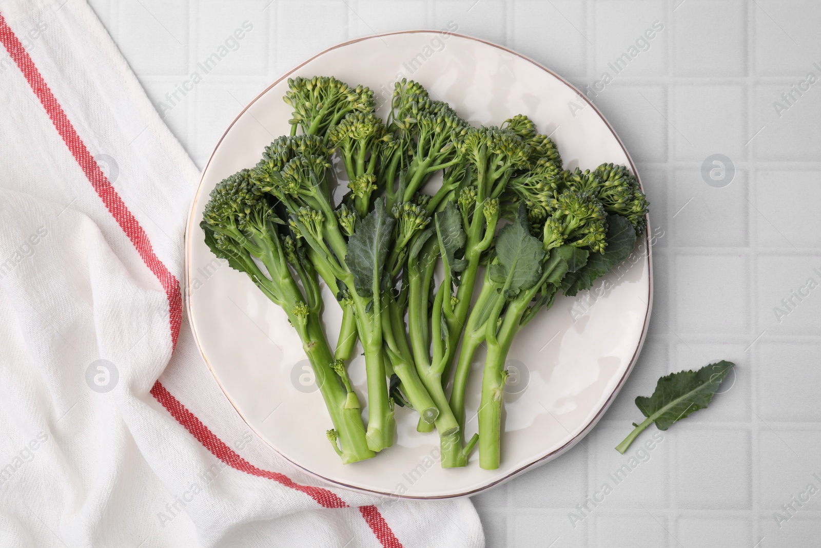 Photo of Fresh raw broccolini on white tiled table, top view. Healthy food