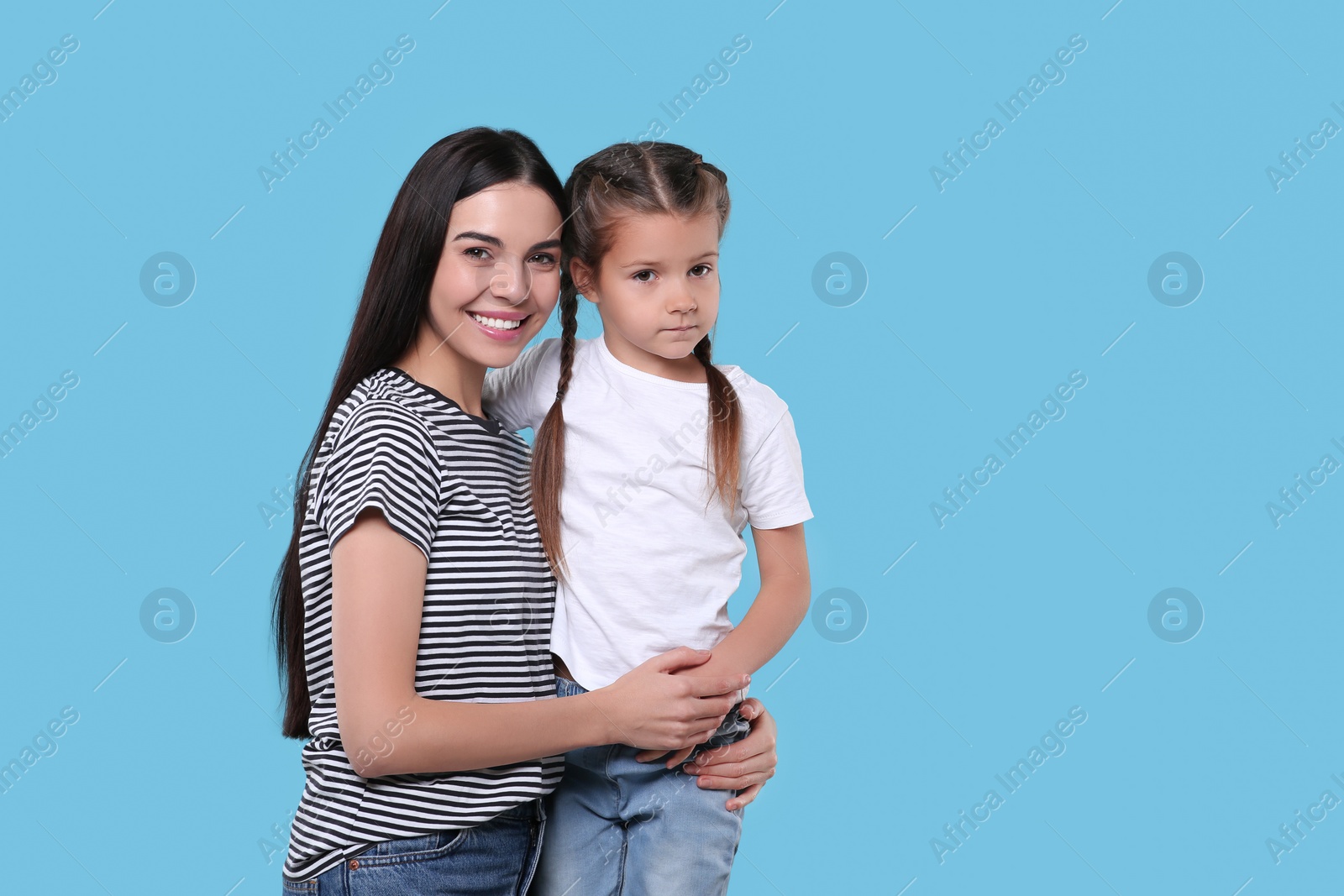 Photo of Happy woman with her cute daughter on light blue background, space for text. Mother's day celebration