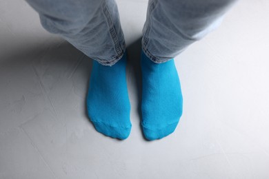 Woman in stylish light blue socks and jeans standing on grey floor, top view
