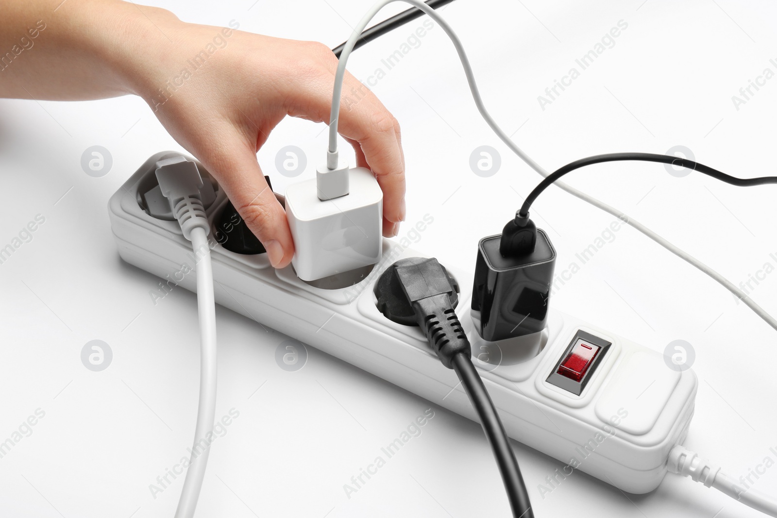 Photo of Woman inserting power plug into extension cord on white background, closeup. Electrician's professional equipment