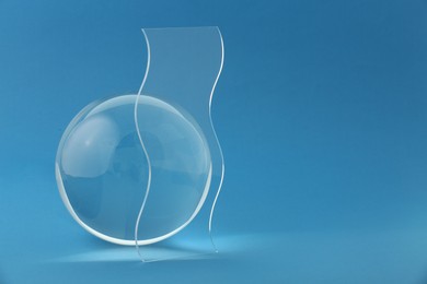 Photo of Composition with transparent glass ball on blue background. Space for text