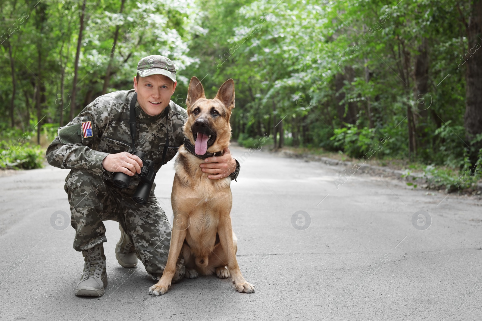 Photo of Man in military uniform with German shepherd dog, outdoors