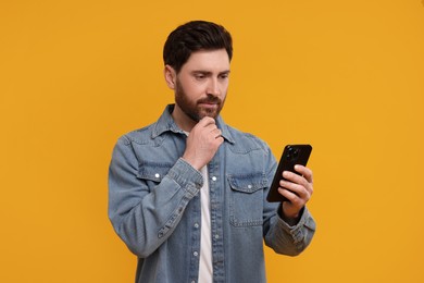 Photo of Handsome man with smartphone on orange background