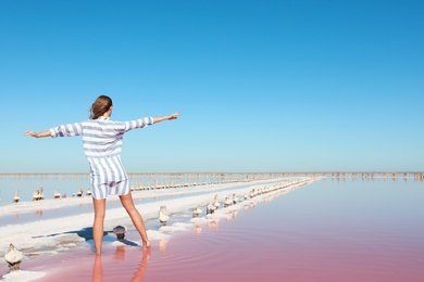 Photo of Beautiful woman posing near pink lake on summer day