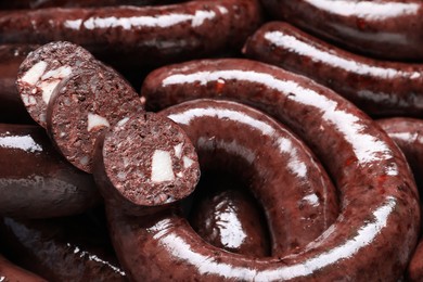 Photo of Cut and whole tasty blood sausages as background, closeup view