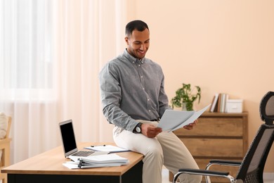 Photo of Happy man working with documents on wooden table in office