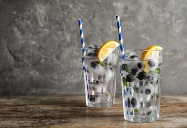 Glasses of drink with blueberry ice cubes on table. Space for text