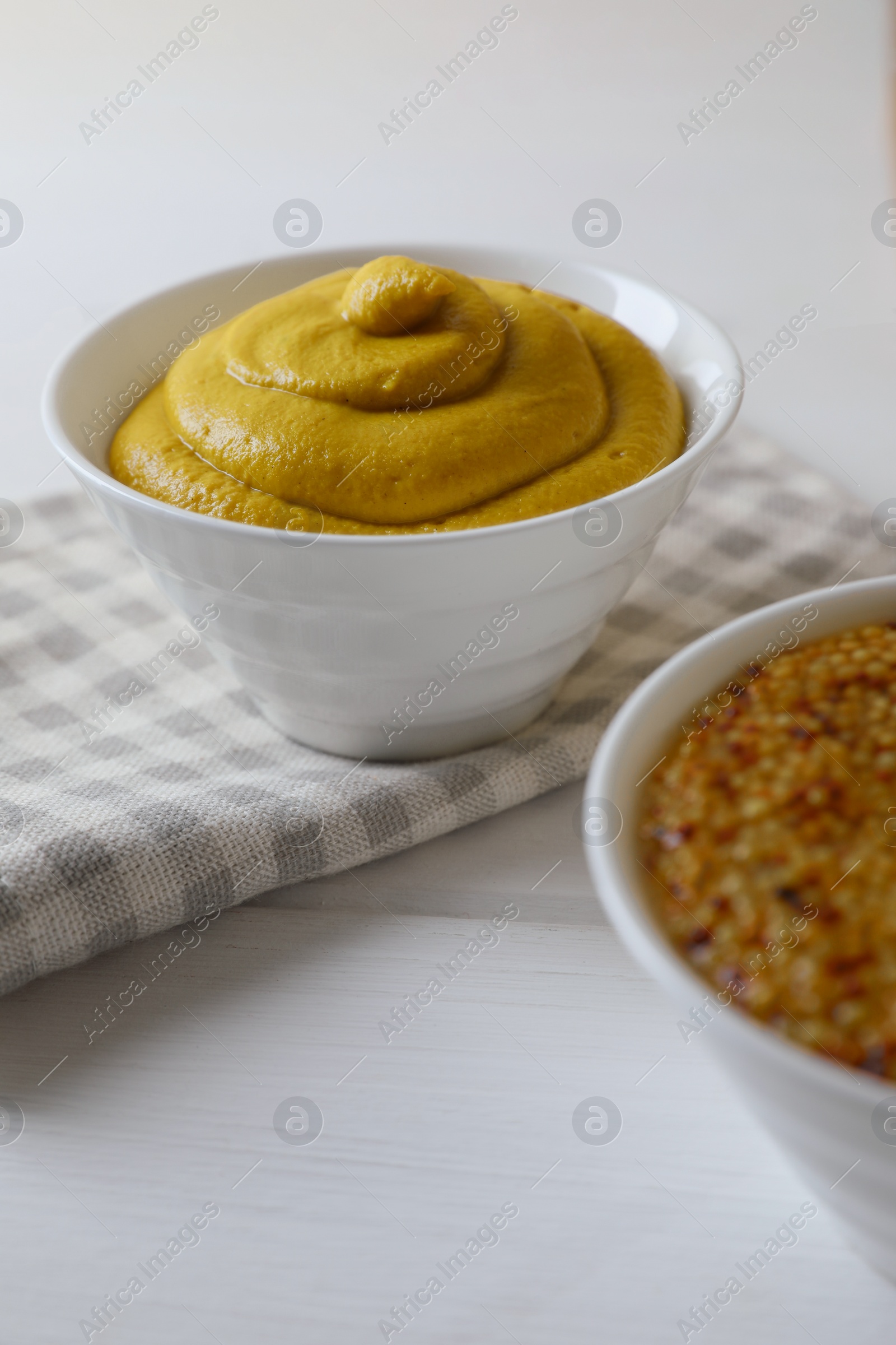 Photo of Bowl of whole grain mustard on white wooden table