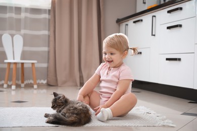 Cute little child with adorable pet on floor at home