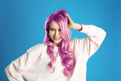 Portrait of young woman with dyed long curly hair on blue background