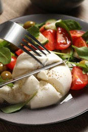 Photo of Delicious burrata salad with arugula, tomatoes and olives on table, closeup