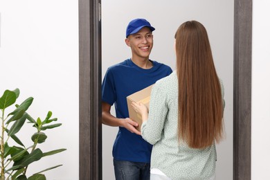 Happy courier giving parcel to receiver indoors