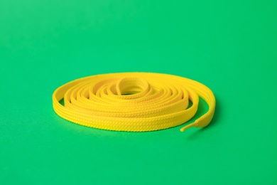 Photo of Yellow shoe lace on green background. Stylish accessory