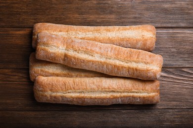 Photo of Tasty baguettes on wooden table, top view