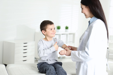 Professional orthopedist examining little patient's arm  in clinic