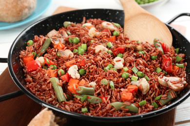 Photo of Tasty brown rice with vegetables on white wooden table, closeup