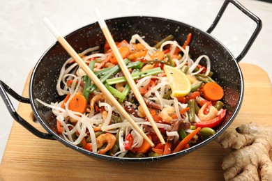 Photo of Shrimp stir fry with noodles and vegetables in wok on table, closeup