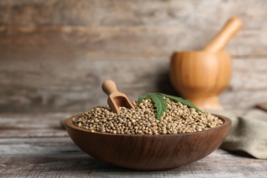 Photo of Bowl of hemp seeds on table against wooden wall