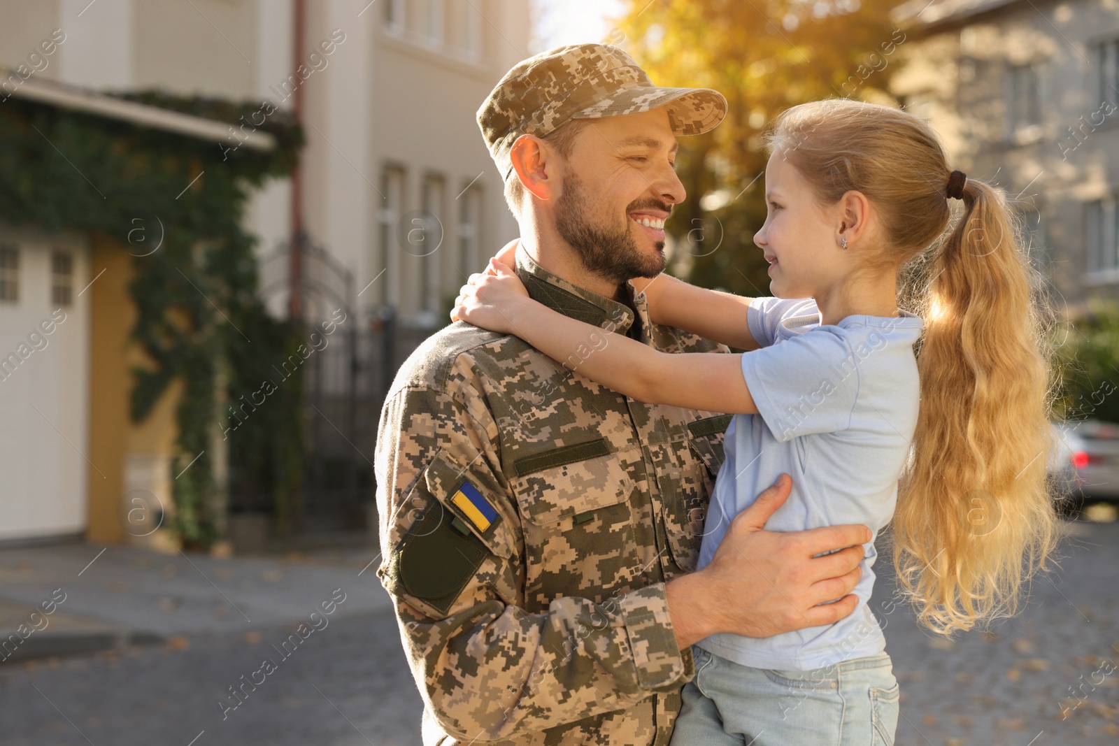 Photo of Father in Ukrainian military uniform and his daughter on city street. Family reunion