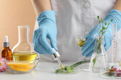 Scientist developing cosmetic oil at white table , closeup