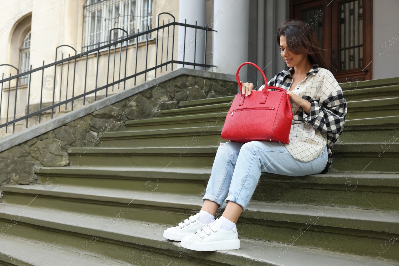 Photo of Young woman with stylish bag on stairs outdoors. Space for text